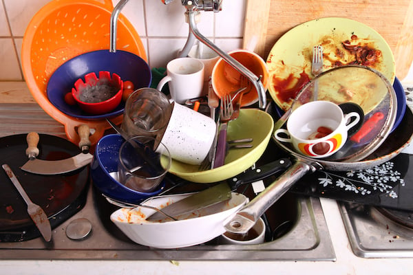 Dirty dishes piled high in a sink
