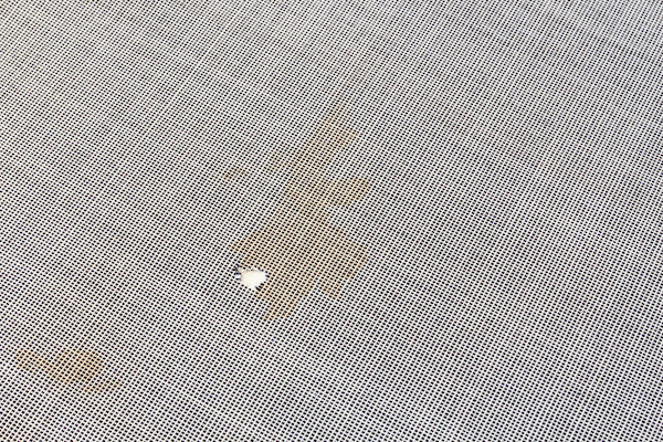 Piece of fabric damaged with holes and stains.