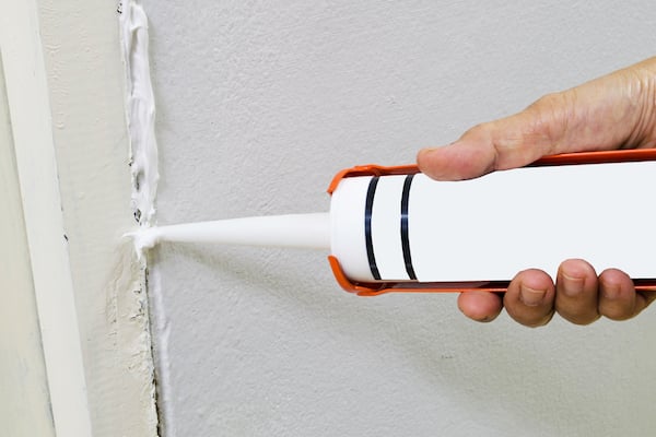 sealing a crack in a wall with caulk